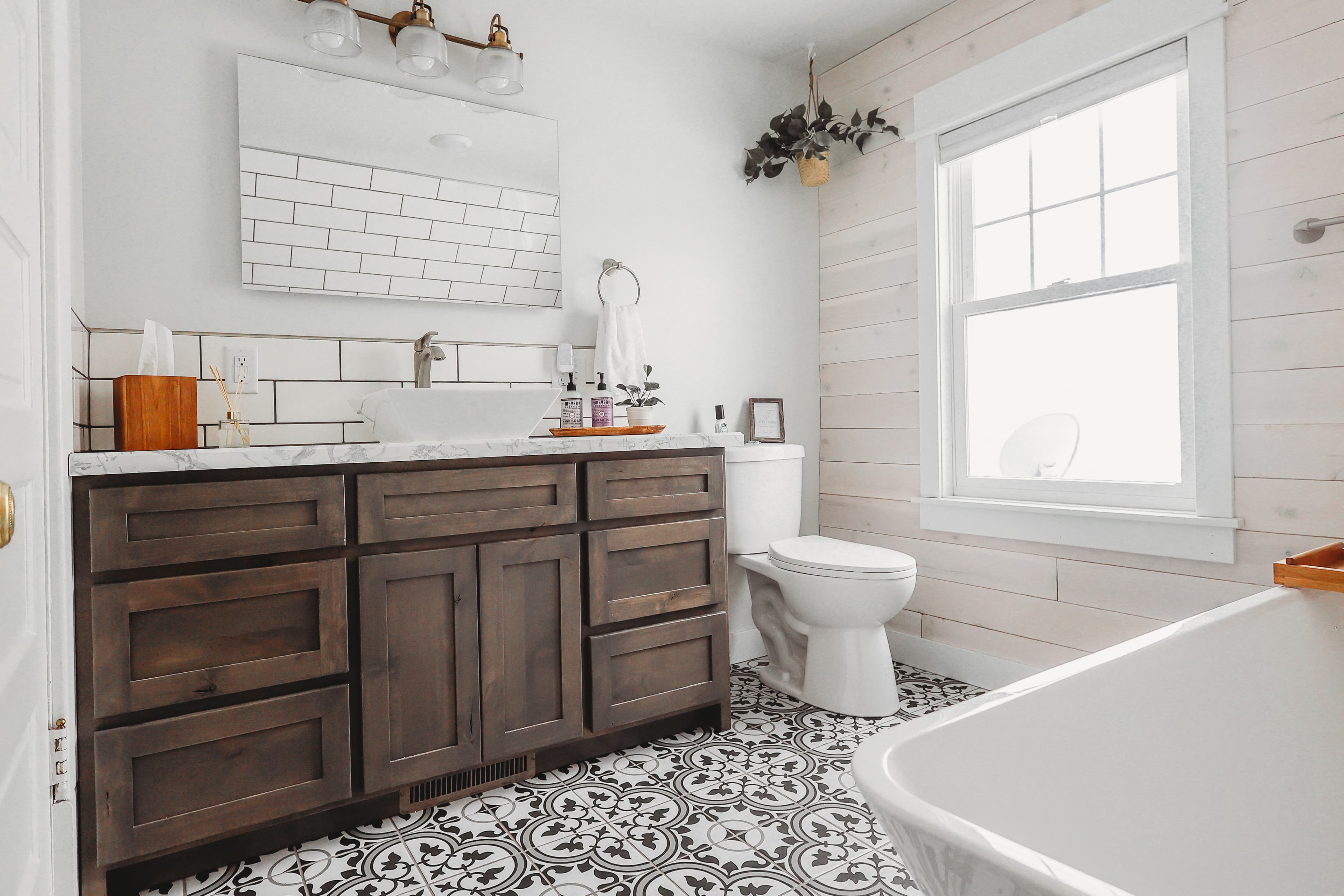 Modern farmhouse bathroom with dark wood vanity, white vessel sink, patterned tiles, and shiplap walls.