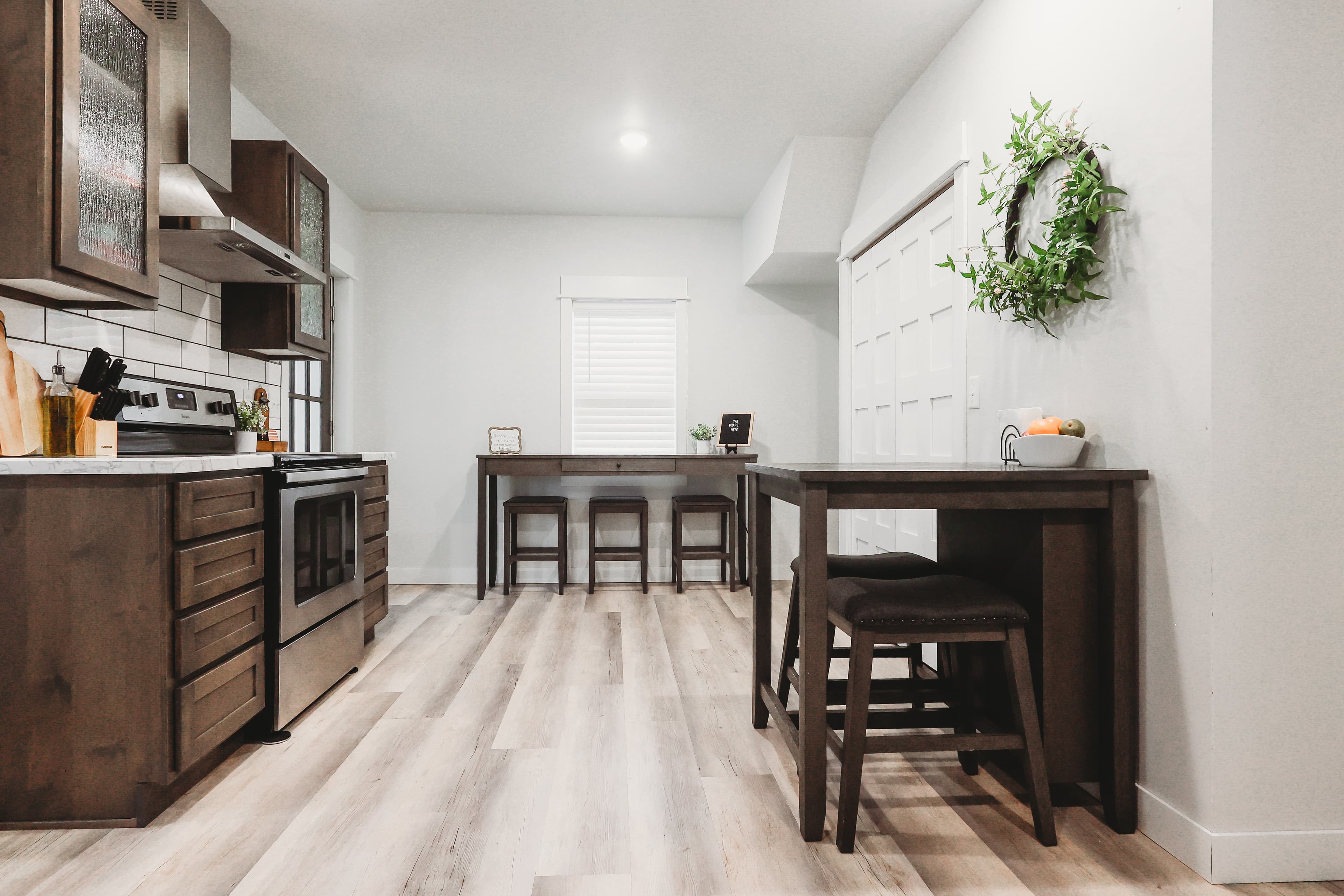Modern kitchen featuring dark wood cabinets, stainless steel appliances, and a dining area with stools.